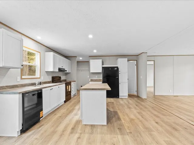 a large kitchen with cabinets wooden floor and stainless steel appliances