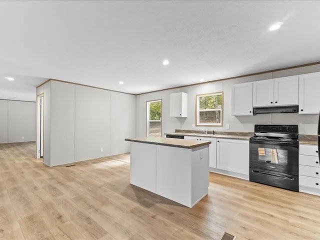 a kitchen with granite countertop a stove top oven and cabinets