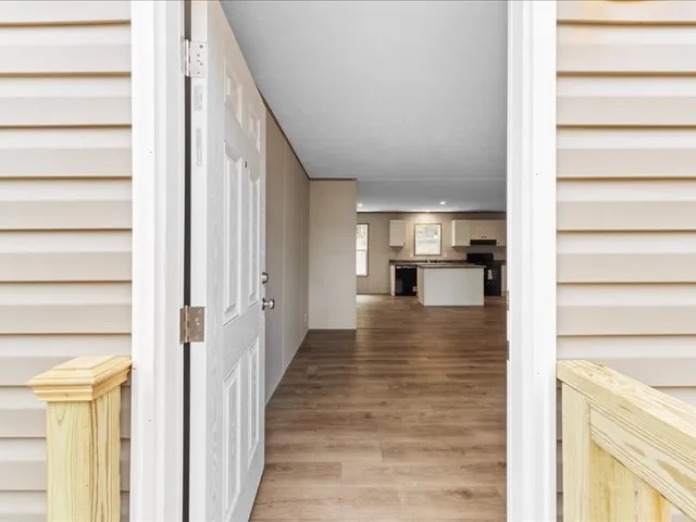 a view of a hallway with wooden floor kitchen view and living room