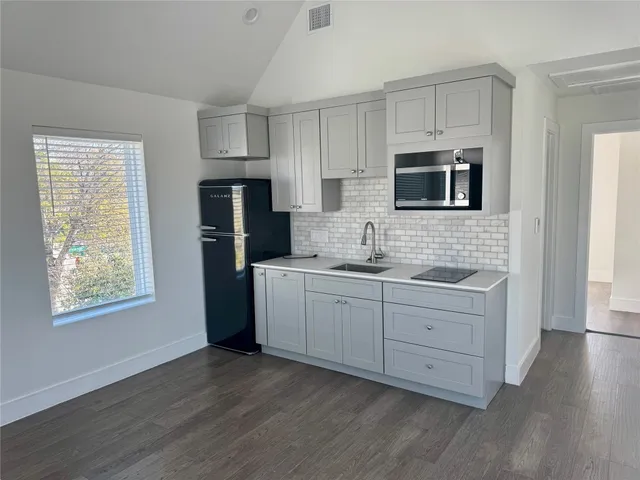 a kitchen with cabinets stainless steel appliances a sink and wooden floor