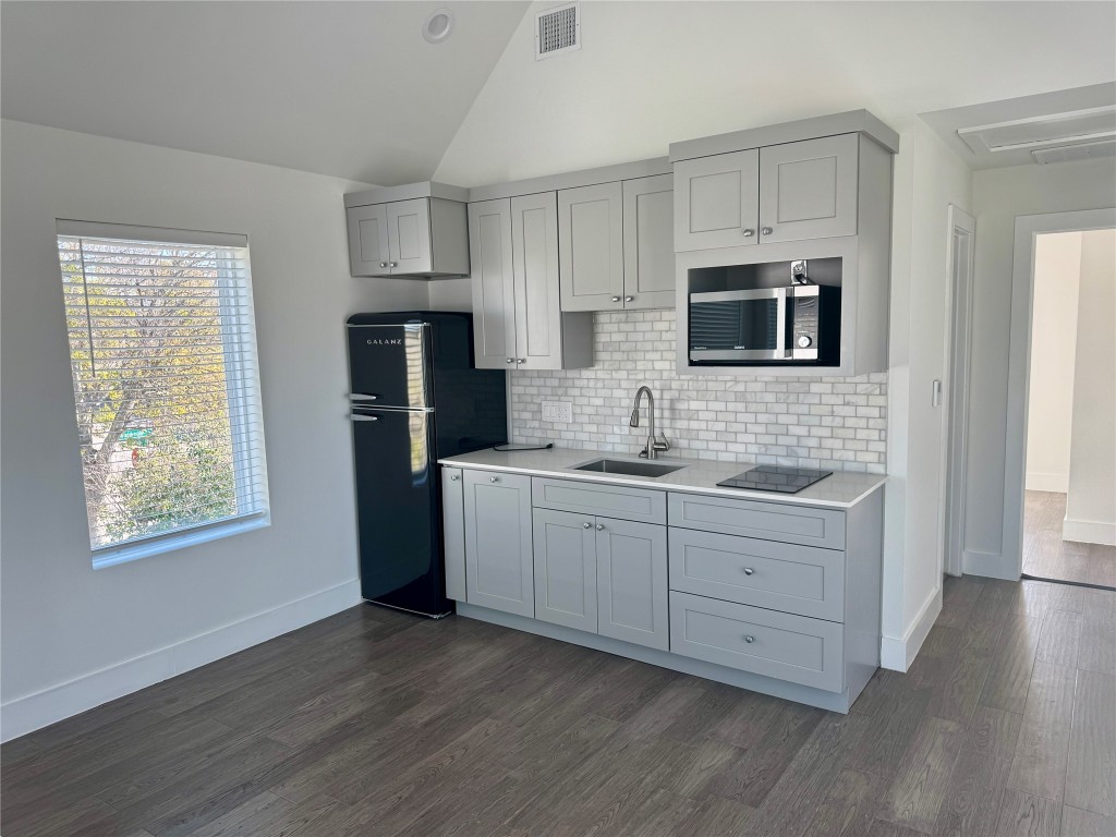 1916 Webberville Road, Unit C Austin, TX 78721 - Photo 3 of 10 a kitchen with cabinets stainless steel appliances a sink and wooden floor