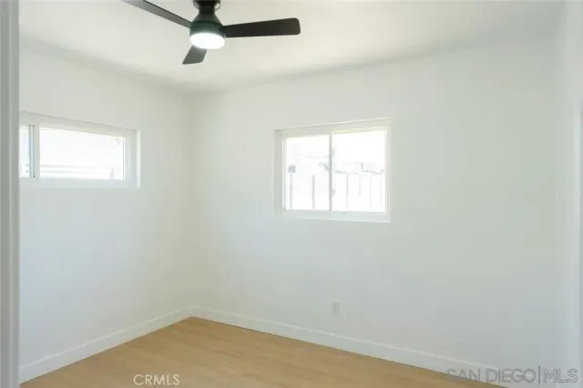 an empty room with a window and a ceiling fan