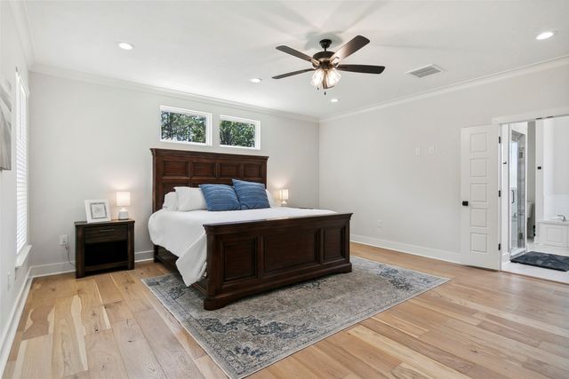 a bed sitting in a spacious bedroom and a night stand