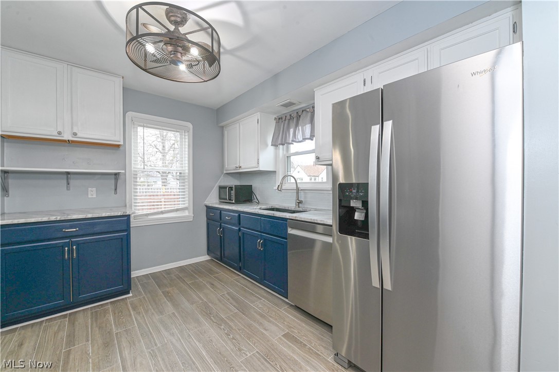 8301 Ackley Road Parma, OH 44129 - Photo 14 of 47 Kitchen with light hardwood / wood-style floors, blue cabinets, appliances with stainless steel finishes, white cabinets, and sink