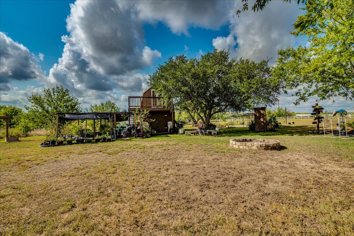 2411 Rohde Road Kyle, TX 78640 - Photo 32 of 40 Mature trees shade a spacious lawn featuring a stone fire pit and multi-level outbuilding.