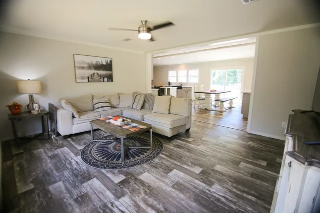 a living room with furniture a large window and wooden floor
