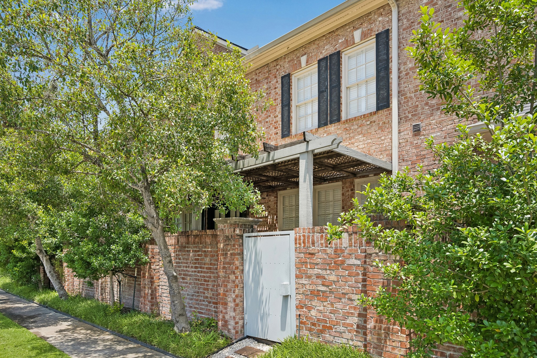 6022 Burgoyne Road Houston, TX 77057 - Photo 27 of 30 Secluded brick-walled courtyard surrounded by mature landscaping, offering privacy and a charming outdoor retreat.