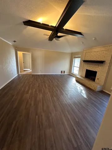 an empty room with wooden floor fireplace and windows