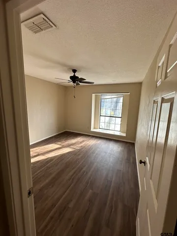 a view of empty room with wooden floor and fan