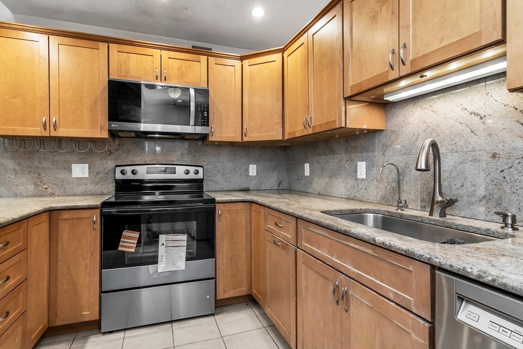 21 Margin Street, Unit 33 Lynn, MA 01905 - Photo 14 of 30 a kitchen with stainless steel appliances granite countertop a sink a stove and a microwave