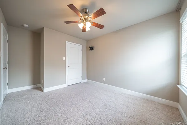 an empty room with a chandelier fan and windows