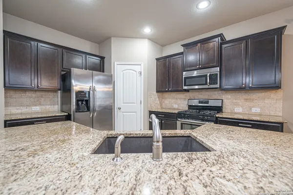 a kitchen with wooden cabinets a refrigerator and a sink