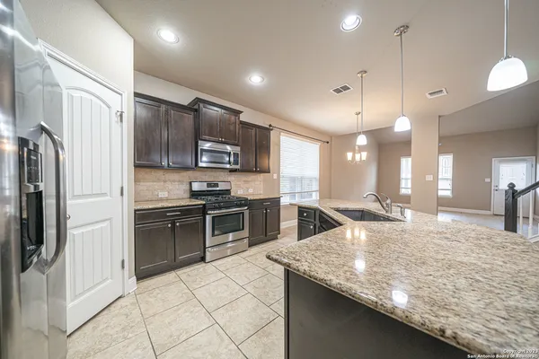 a large kitchen with granite countertop a large counter top stainless steel appliances and cabinets