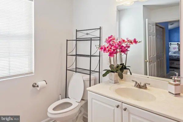 a bathroom with a toilet sink vanity granite and mirror