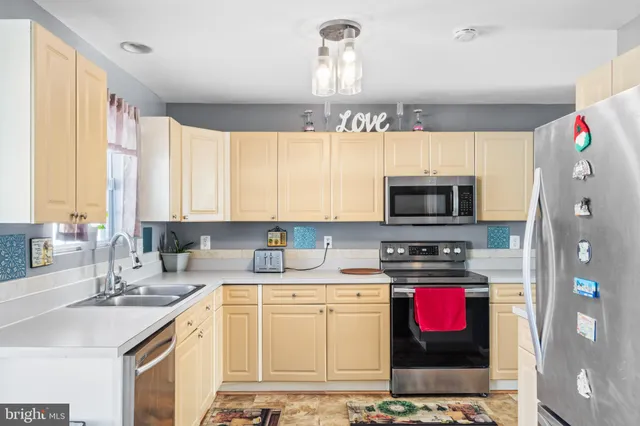 a kitchen with stainless steel appliances a sink a stove a microwave a refrigerator and cabinets