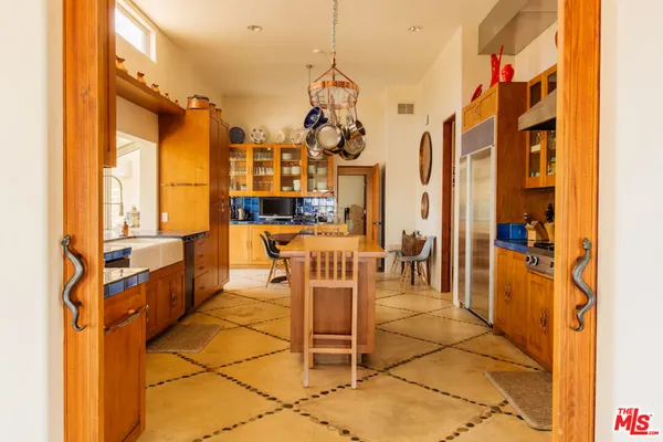 a kitchen with cabinets a island and chairs in it