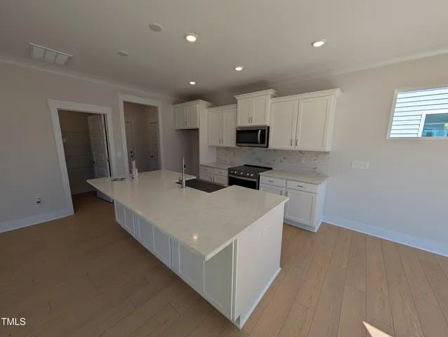 a large white kitchen with wooden floor