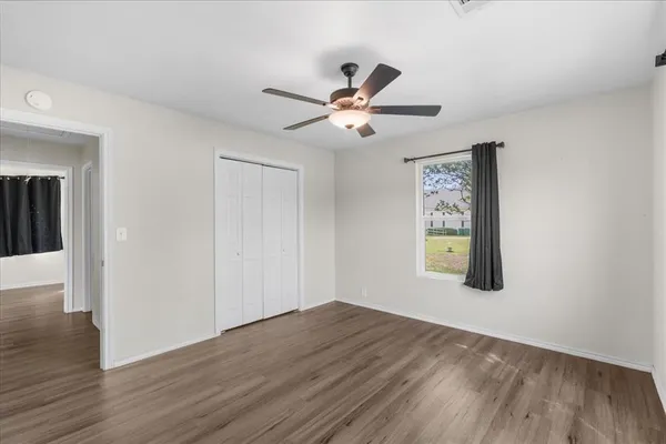 a view of empty room with wooden floor and fan