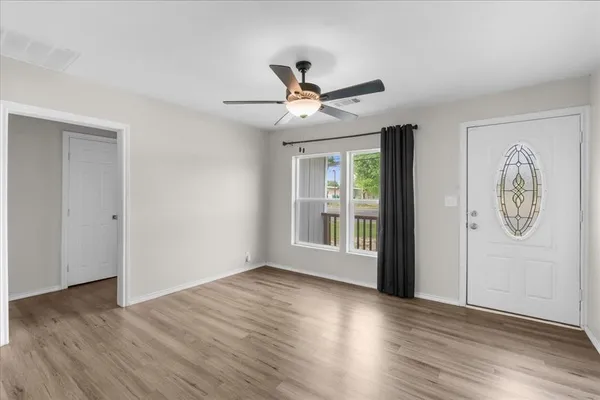 an empty room with wooden floor chandelier fan and windows