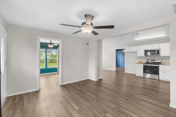 a view of kitchen with microwave a stove and wooden floor