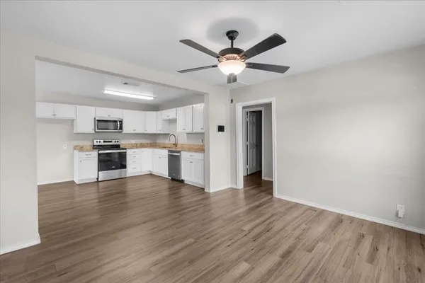 a view of kitchen with wooden floor a sink and appliances