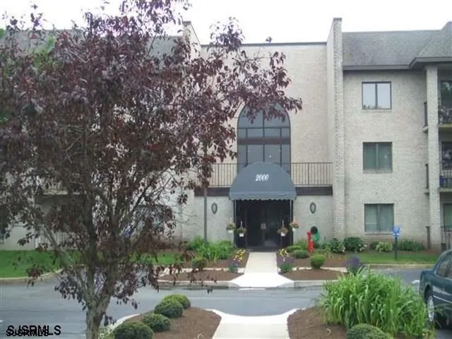 a front view of a house with garden and trees