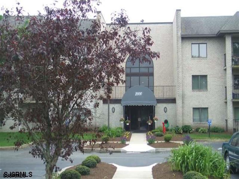 a front view of a house with garden and trees