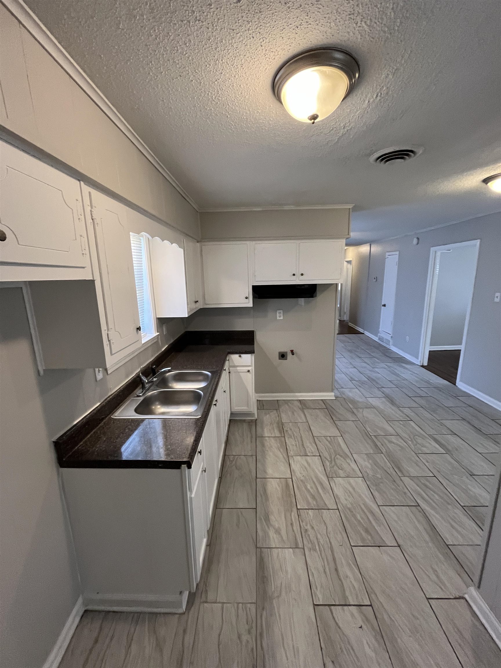 3973 Brompton Road Memphis, TN 38118 - Photo 4 of 17 Kitchen featuring a textured ceiling, visible vents, dark countertops, white cabinetry, and a sink