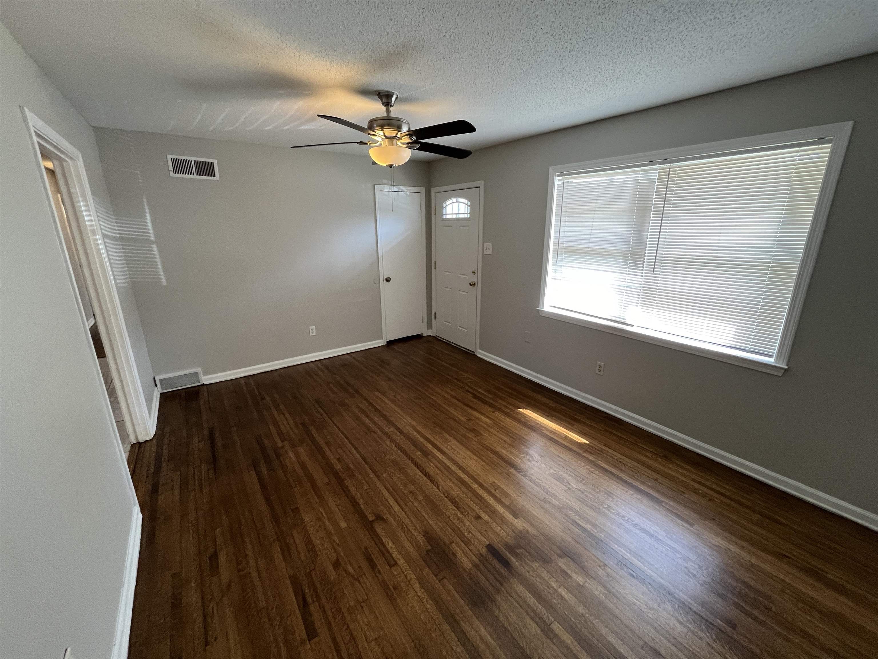 3973 Brompton Road Memphis, TN 38118 - Photo 7 of 17 Empty room with a textured ceiling, visible vents, baseboards, ceiling fan, and wood finished floors