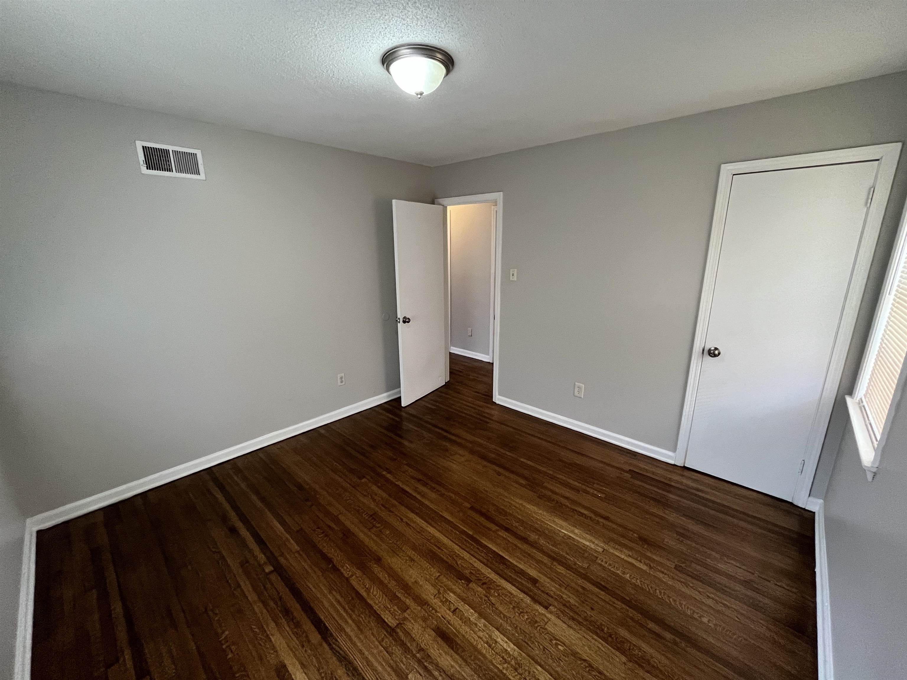 3973 Brompton Road Memphis, TN 38118 - Photo 10 of 17 Empty room with dark wood-style floors, visible vents, baseboards, and a textured ceiling