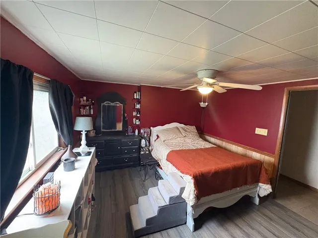 a bedroom with a bed a dresser with wooden floor