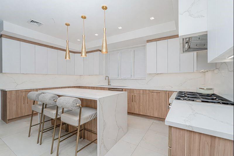 104 Village Road South Brooklyn, NY 11223 - Photo 14 of 36 a kitchen with a table chairs stove and white cabinets