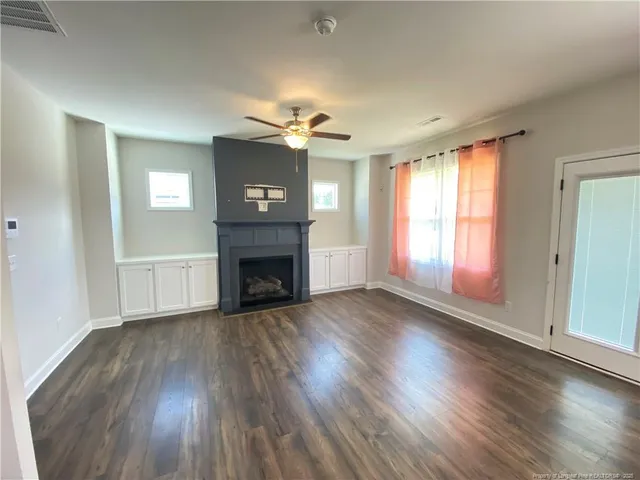 an empty room with wooden floor fireplace and windows