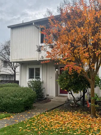 a view of a white house with a yard table and chairs