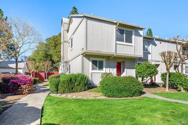 a view of a big building with a big yard plants and large trees