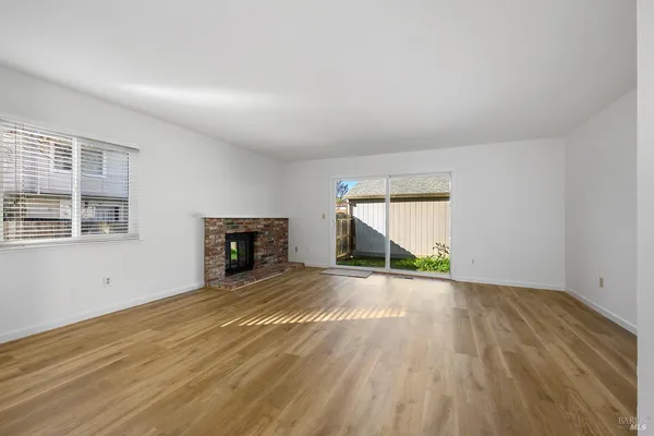 a view of empty room with wooden floor and fireplace