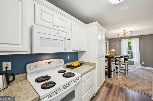 a kitchen with a sink a stove and white cabinets with wooden floor