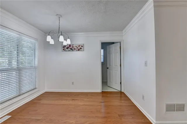 an empty room with wooden floor cabinet and windows