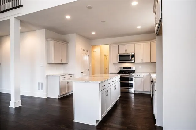 a kitchen with stainless steel appliances granite countertop a stove top oven a sink dishwasher and a refrigerator with wooden floor