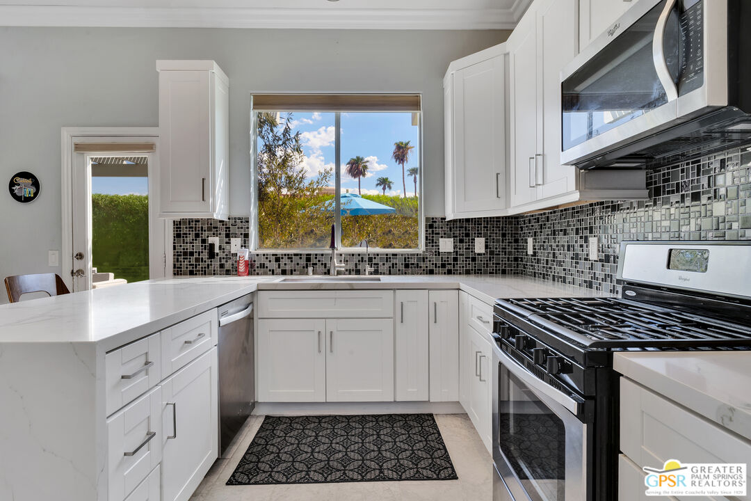 68315 Riviera Road Cathedral City, CA 92234 - Photo 16 of 33 a kitchen with stainless steel appliances a stove a sink cabinets and a window