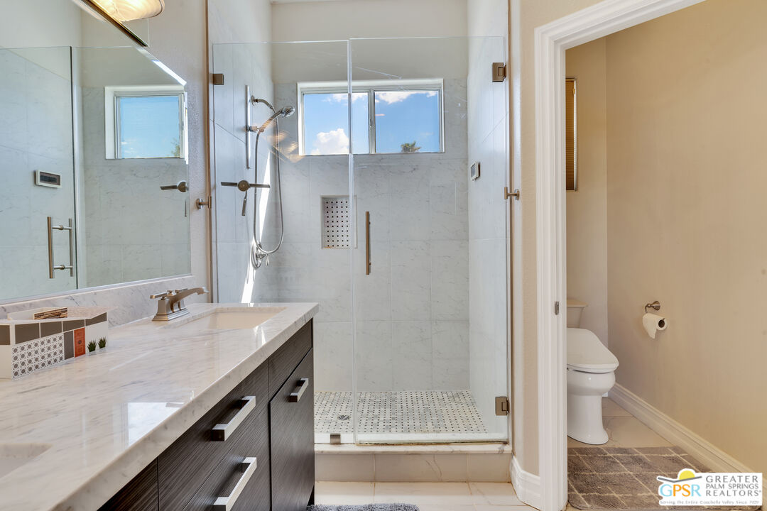 68315 Riviera Road Cathedral City, CA 92234 - Photo 27 of 33 a bathroom with a granite countertop sink a toilet and shower