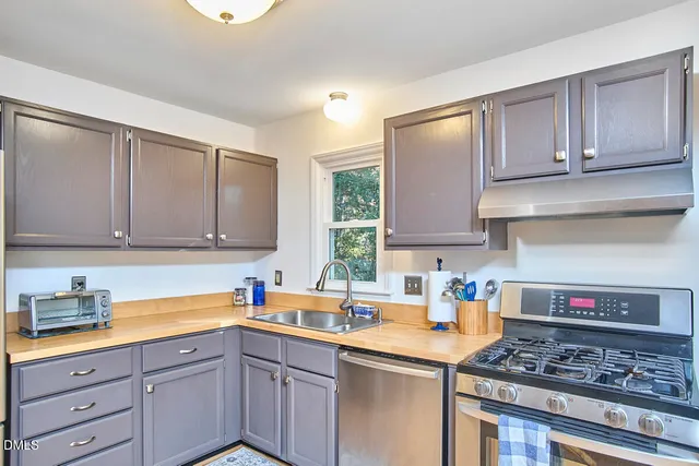 a kitchen with stainless steel appliances granite countertop a refrigerator a sink and wooden cabinets