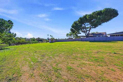 a view of a pool with lawn chairs and a big yard
