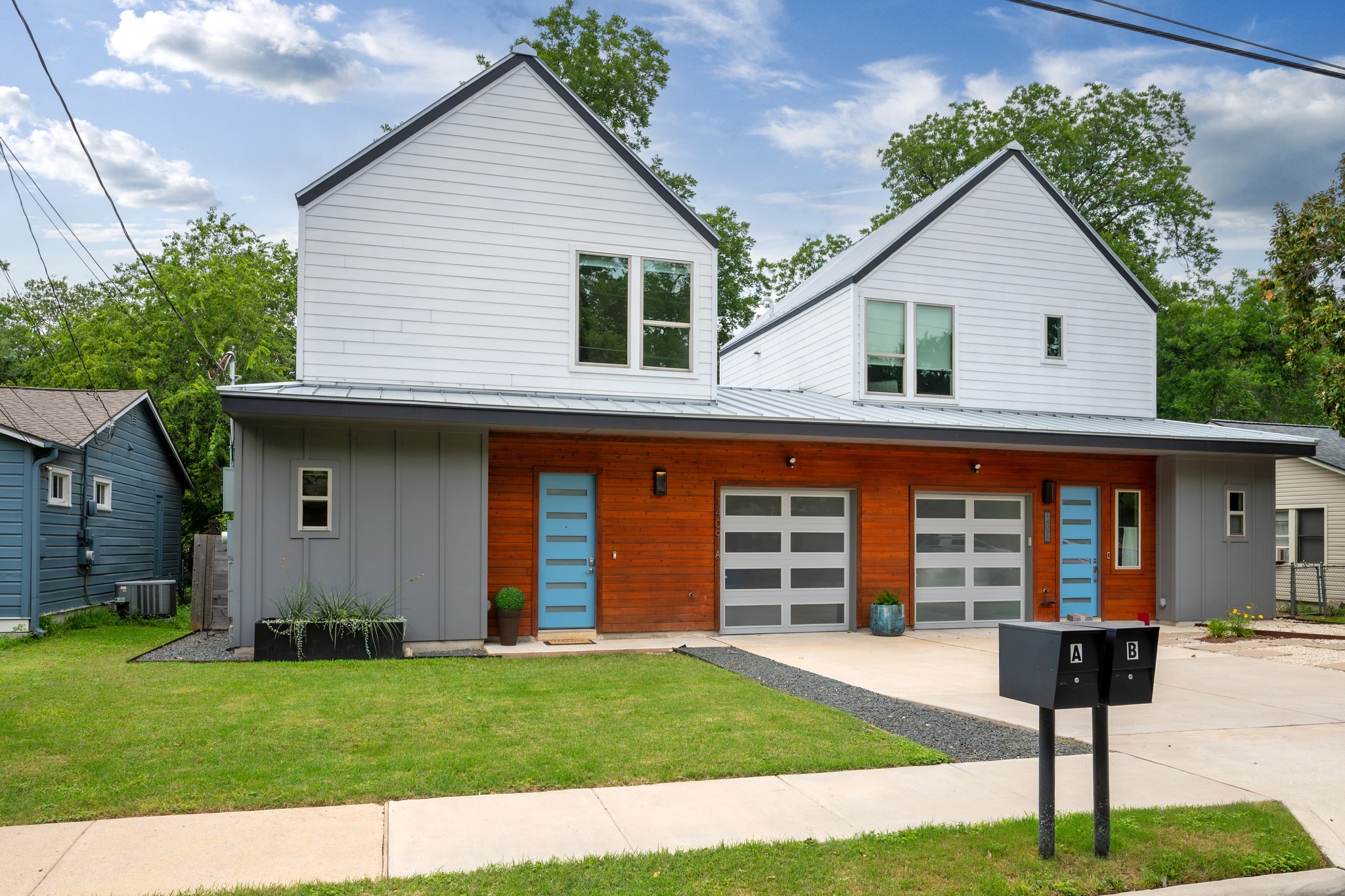 1409 Alegria Road, Unit A Austin, TX 78757 - Photo 2 of 24 Modern architecture pairs white siding with warm wood accents and contemporary garage doors for inviting curb appeal.
