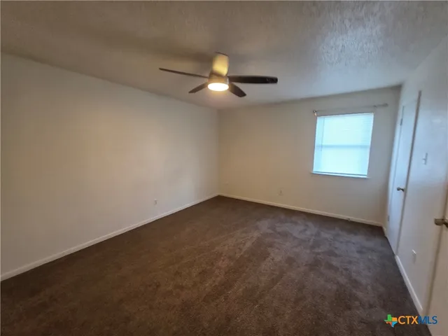 an empty room with a window and a fan