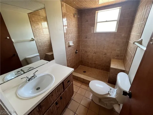 a bathroom with a sink vanity granite tub and toilet