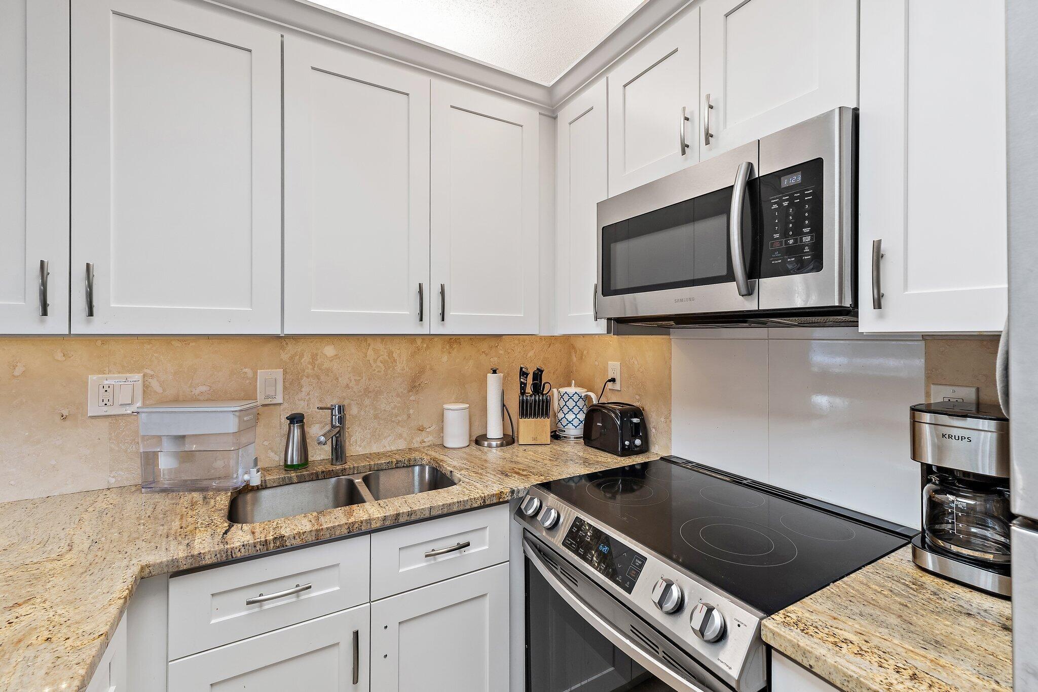 353 Highway 1, Unit C7 Jupiter, FL 33477 - Photo 12 of 45 a kitchen with stainless steel appliances granite countertop white cabinets and a stove top oven