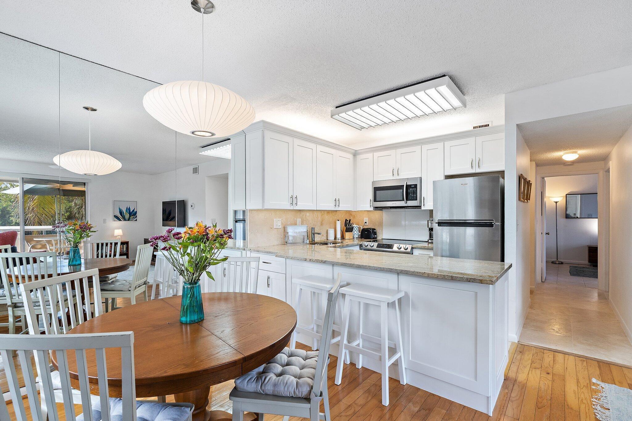 353 Highway 1, Unit C7 Jupiter, FL 33477 - Photo 8 of 45 a kitchen with stainless steel appliances granite countertop a stove refrigerator a dining table and chairs with wooden floor