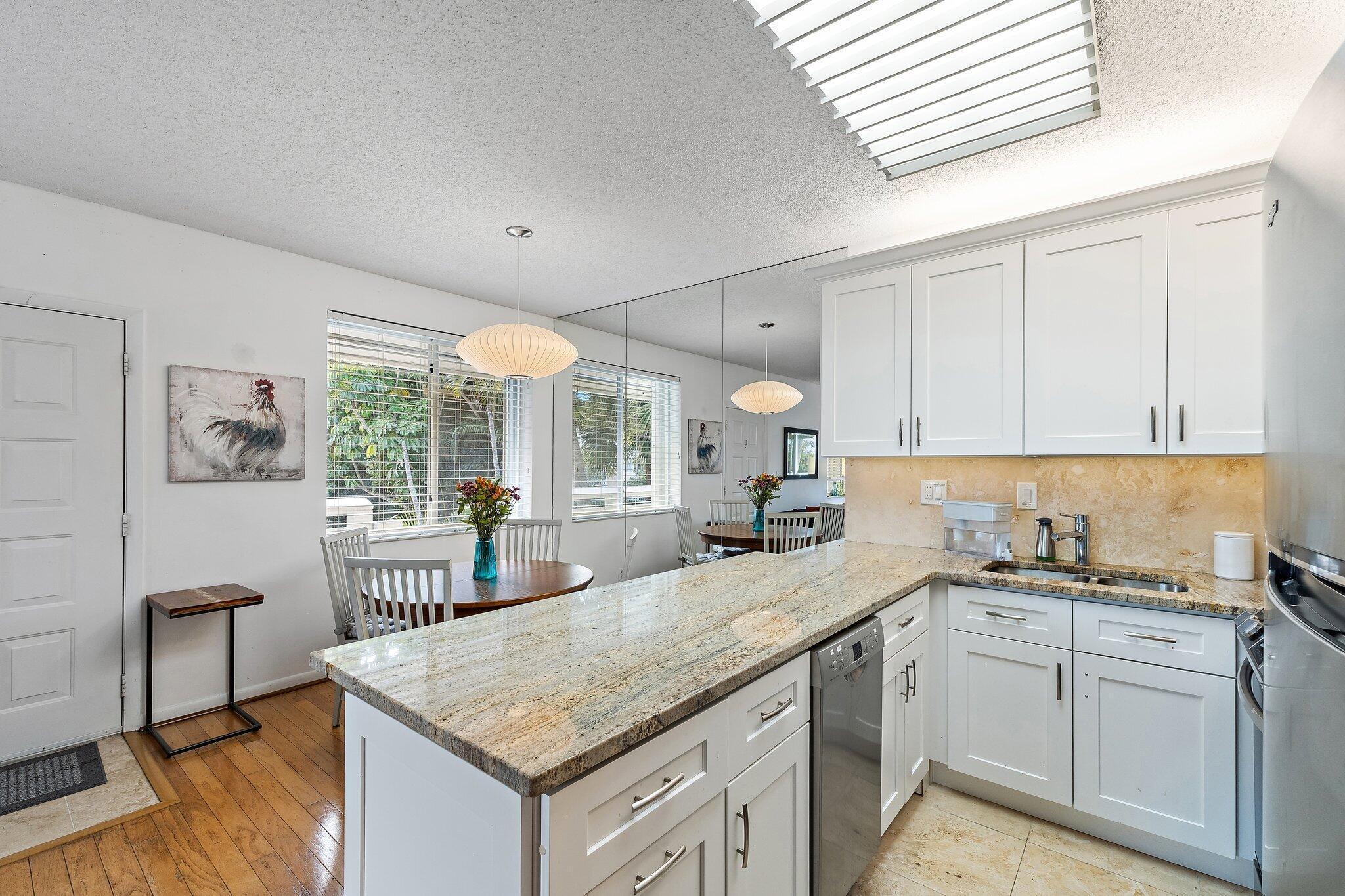 353 Highway 1, Unit C7 Jupiter, FL 33477 - Photo 10 of 45 a kitchen with a sink dishwasher a stove a dining table and chairs with wooden floor