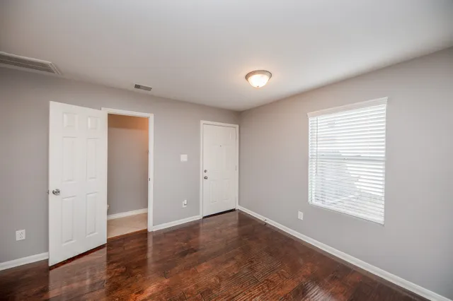 an empty room with wooden floor and windows